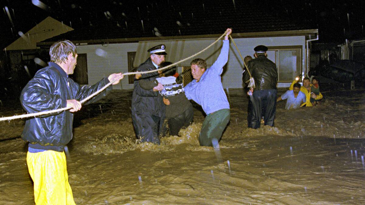 Police and workers help a family to safety from their flooding Figtree home in 1998.