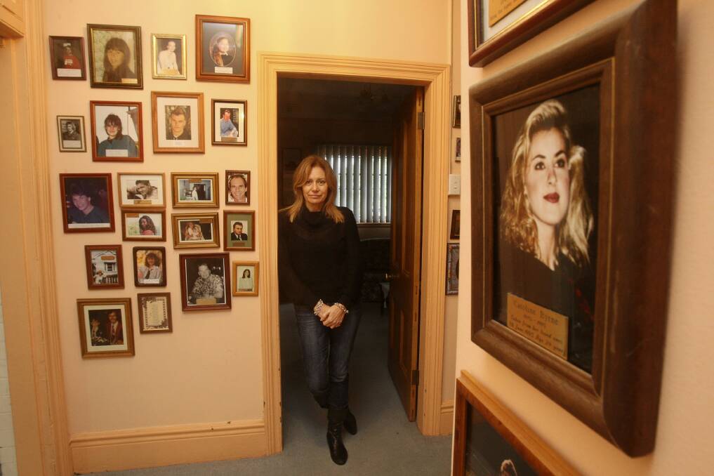 Mary Cusumano surrounded by the photos of murder victims at the "Wall of Fame" at Ebony House. 