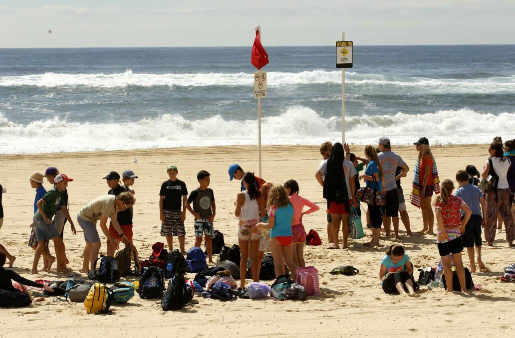 Swimmers stranded on the shore at Nobbys. More shark sightings on Tuesday have forced lifeguards to shut the beaches again. Pic: Darren Pateman
