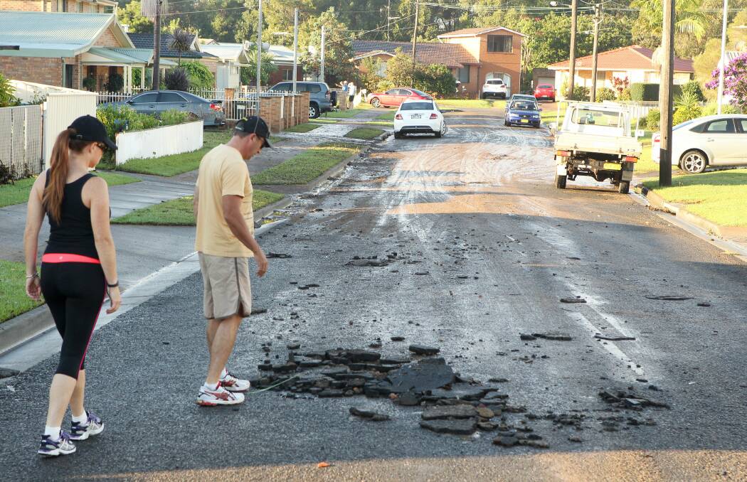 Early morning walkers inspect damage to the road surface in Benelong Street, Bulli. Picture: KIRK GILMOUR