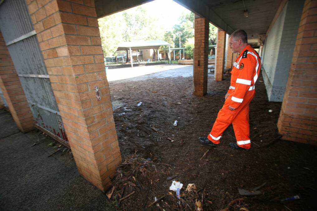 An SES worker inspects the damage at Bulli High School.The organisation has responded to more than 400 calls for help in the last 48 hours, Picture: KIRK GILMOUR