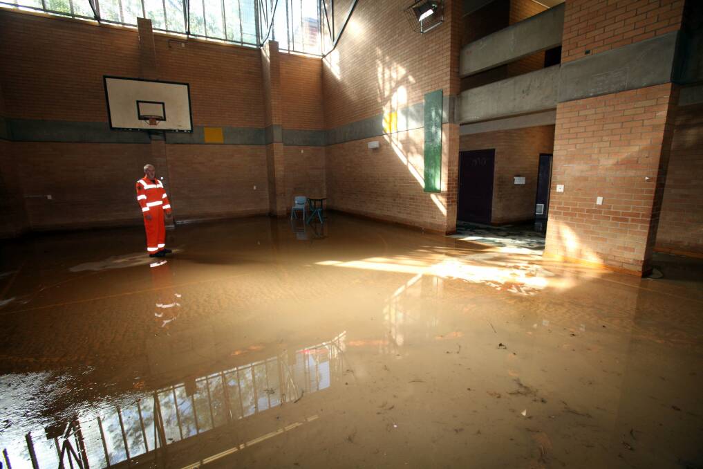 An SES worker inspects the damage to the Bulli High School gym. Picture: KIRK GILMOUR