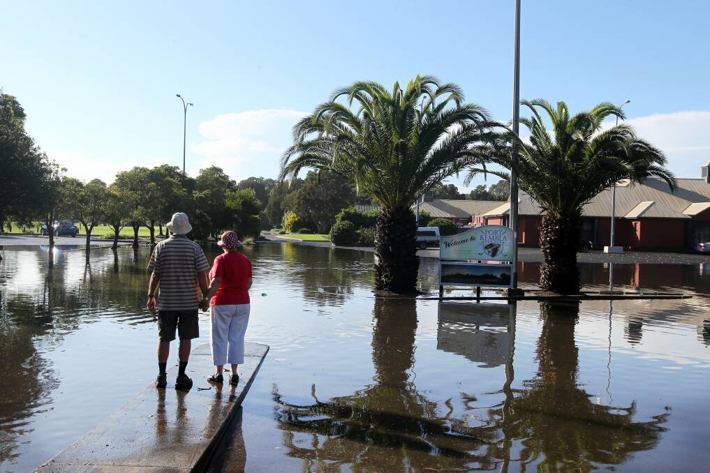 Laurie and Cathy Bridge inspect the flooded entrance to Port Kembla Golf Club. Picture: SYLVIA LIBER
