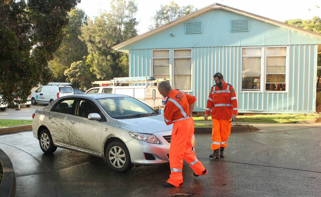  SES personnel look at a damaged car in the car park at Bulli High School. Picture: KIRK GILMOUR