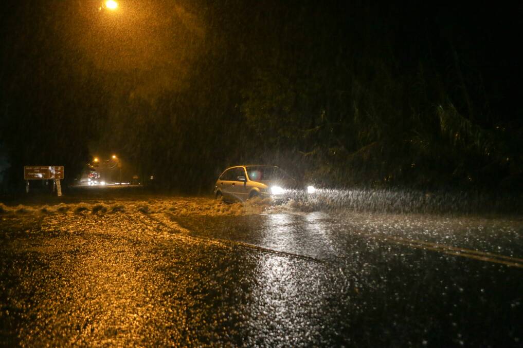 Cars crossing floodwaters across the Princes Highway in Berry. Picture: CHRISTOPHER CHAN