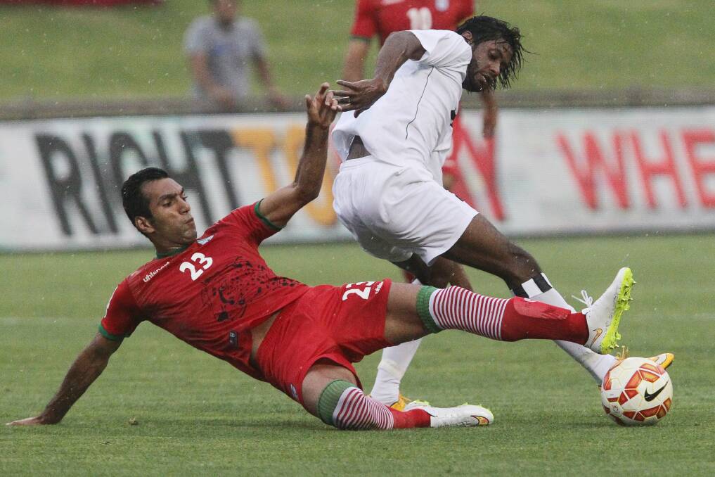 Iran's Mehrdad Pooladi slides in to challenge Iraq player Amjed Kalaf Al-Muntafik during the Asian Cup warm-up friendly at WIN Stadium on Sunday. Picture: GREG TOTMAN