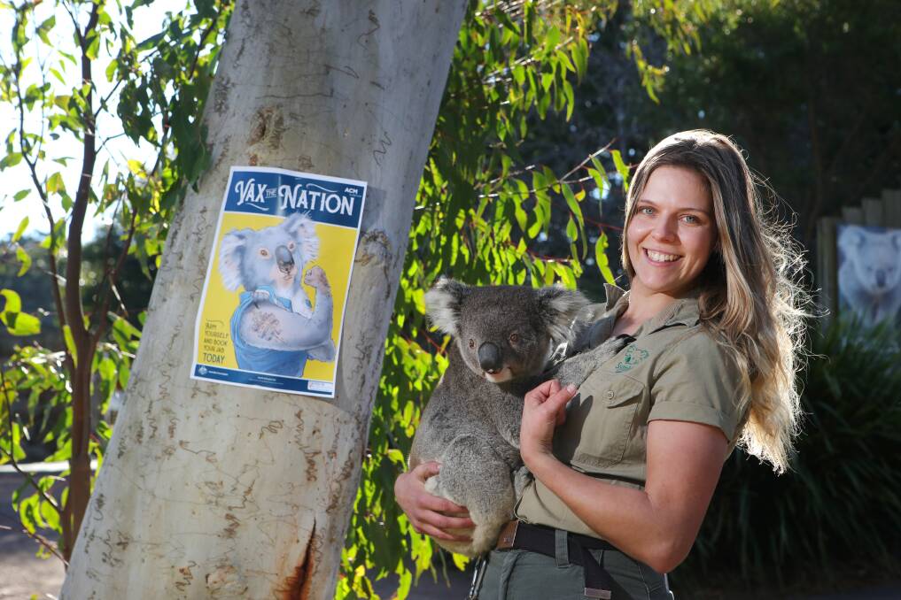 Free vaccination poster: Native zookeeper Elizabeth Florance and Johnny the koala arm themselves in front of a Vax The Nation poster at Symbio Wildlife Park. Picture: Sylvia Liber.