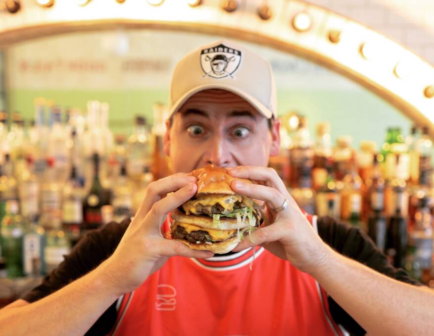 Big Challenge: Lachlan Stevens hooking into the Four Patty Fat Boy created for International Burger Day to support the Homeless Hub. Picture: His Boy Elroy.