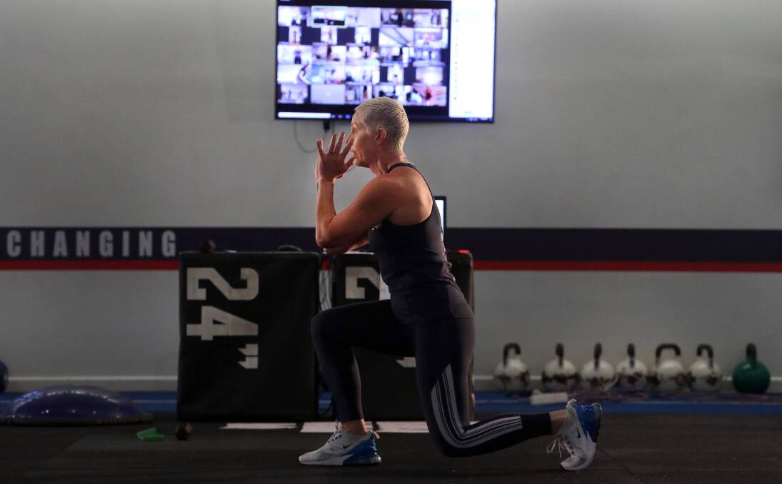 Global reach: Kerrie Lawrence leads a fitness class online at the closed F45 Studio in Shellharbour surrounded by screens with people from around the world joining in on the zoom app. Picture: Robert Peet. 
