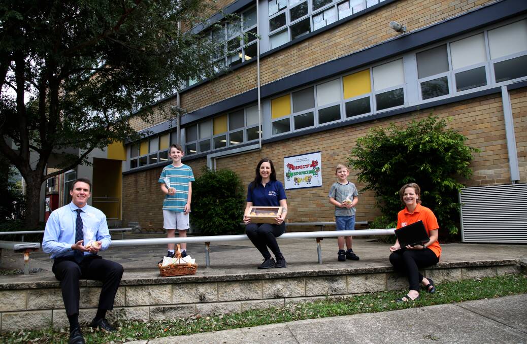 St Columbkille's Catholic Parish Primary School principal Brad Colquhourn receives the home made biscuits from Samuel, Amber and Archer Morrisey and one of the Illawarra Kindness Pandemic page administrators Natasha Debsieh, of Age Matters. Picture: Greg Ellis. .