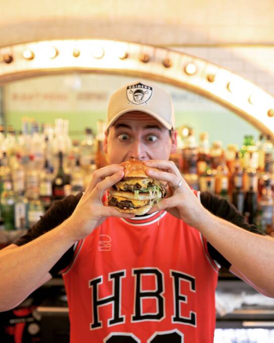 Big Challenge: Lachlan Stevens hooking into the Four Patty Fat Boy created for International Burger Day to support the Homeless Hub. Picture: His Boy Elroy. 