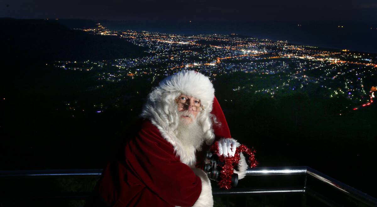 OH WHAT A GLORIOUS NIGHT: Santa with the lights of Wollongong's northern suburbs glowing brightly behind him before delivering his special message. Picture: Robert Peet.