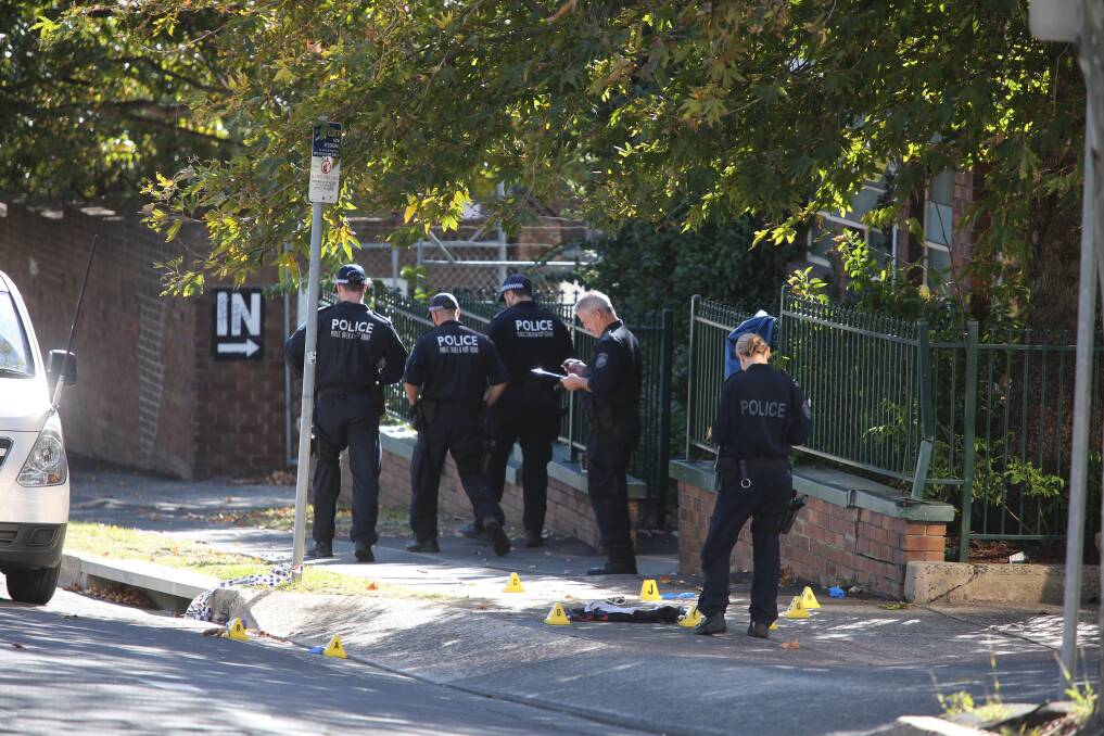 SEARCH: Police officers assess the scene of the stabbing outside the Denison Street methadone clinic.