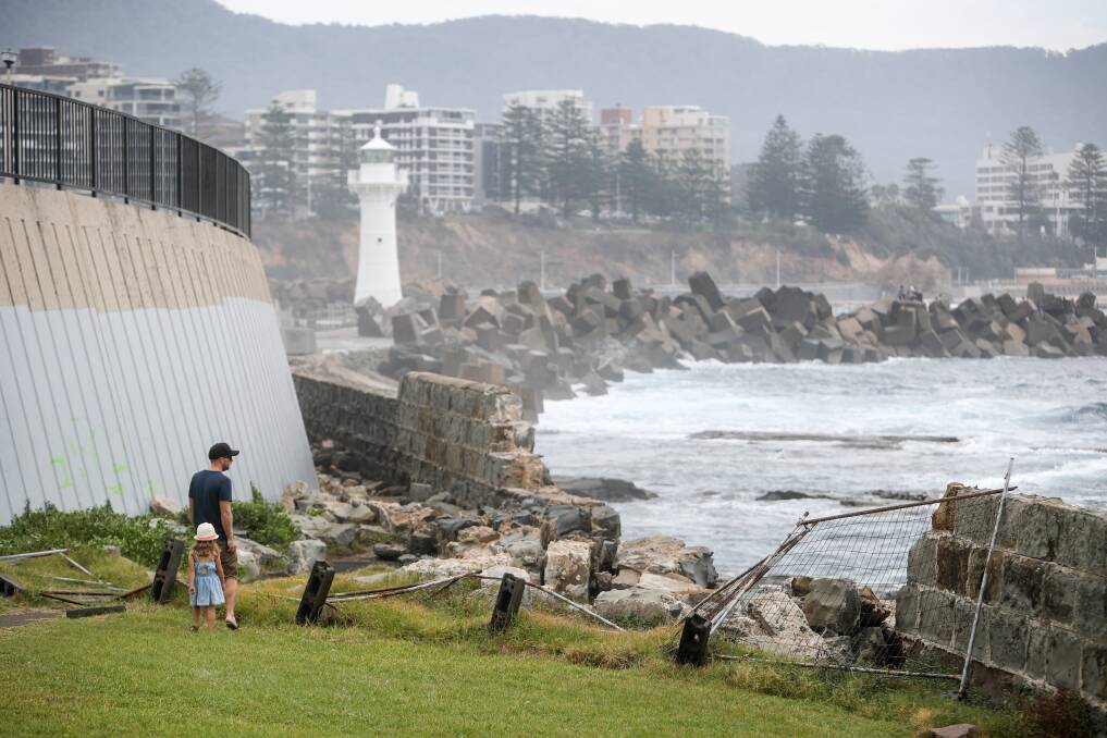 Passersby examine the remains of the damaged seawall, which sit behind a toppled temporary fence, at Flagstaff Hill. Picture: Adam McLean
