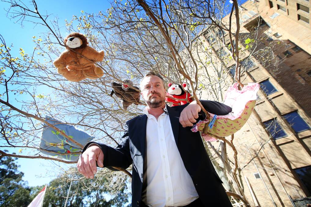 Public Service Association (PSA) assistant general secretary Troy Wright among pillows hanging in a tree to highlight the plight of children statewide who call a hotel or motel room home every night. Picture: Sylvia Liber