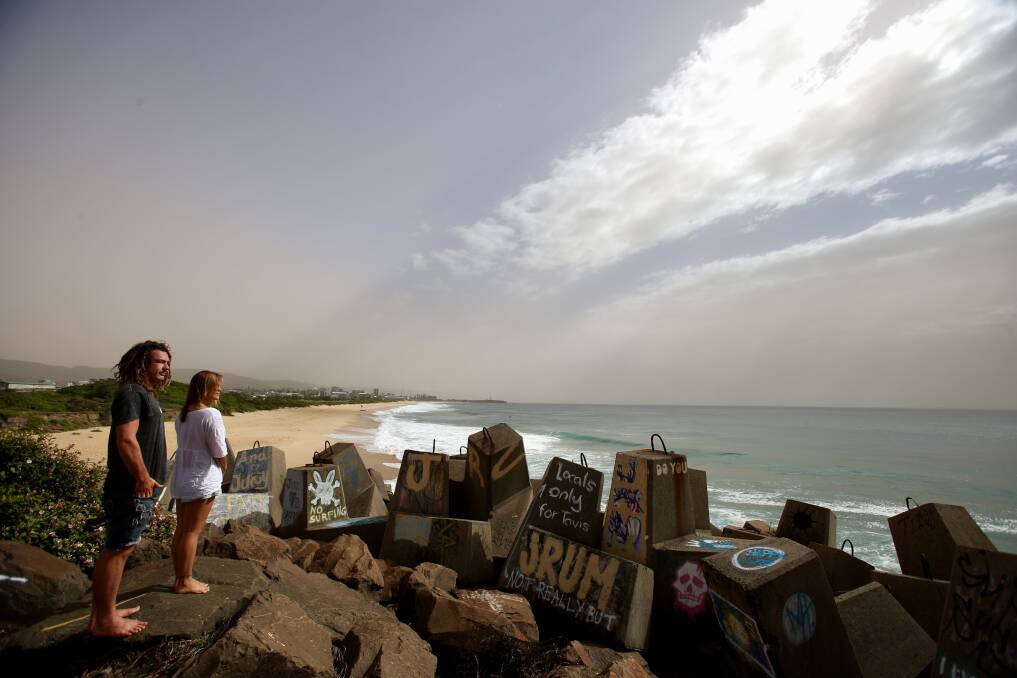 SPECTACLE: Scott Fuller and Natalie Beekmann check out the dust cloud, from the breakwater near the Port Kembla coal loader, as it rolls across Wollongong and out to sea.