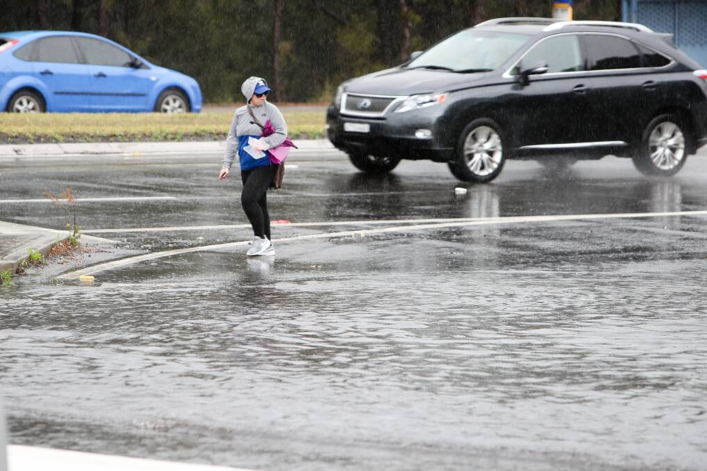 A pedestrian navigates a large puddle at the intersection of Springhill Road and Bridge Street at Coniston late last month. Picture: Adam McLean
