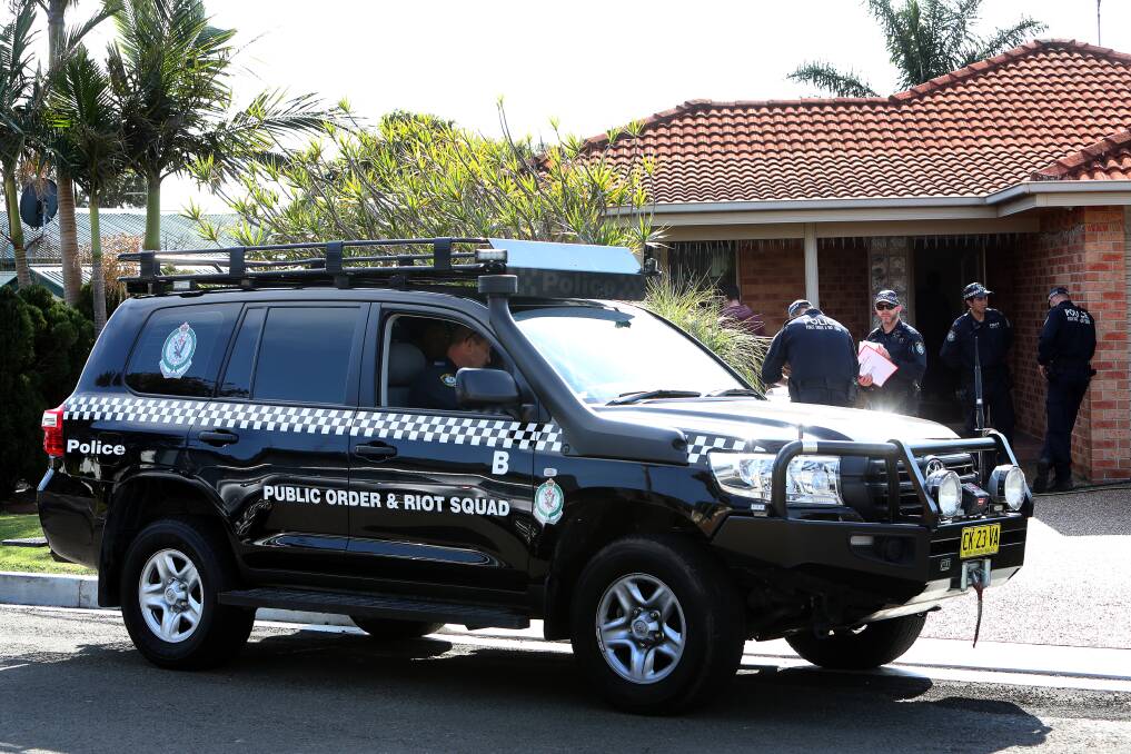 Members of the NSW Police Public Order and Riot Squad outside a home on Edward Street, Barrack Heights on Wednesday. The home was one of seven raided as part of an ongoing police operation led by Strike Force Raptor.