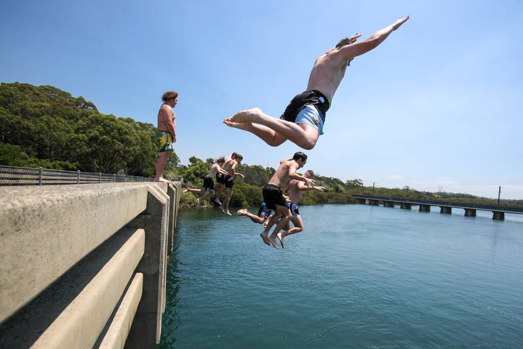 KEEPING COOL: A group of people jump off the Riverside Drive bridge into the Minnamurra River to beat the heat this week. Picture: Adam McLean
