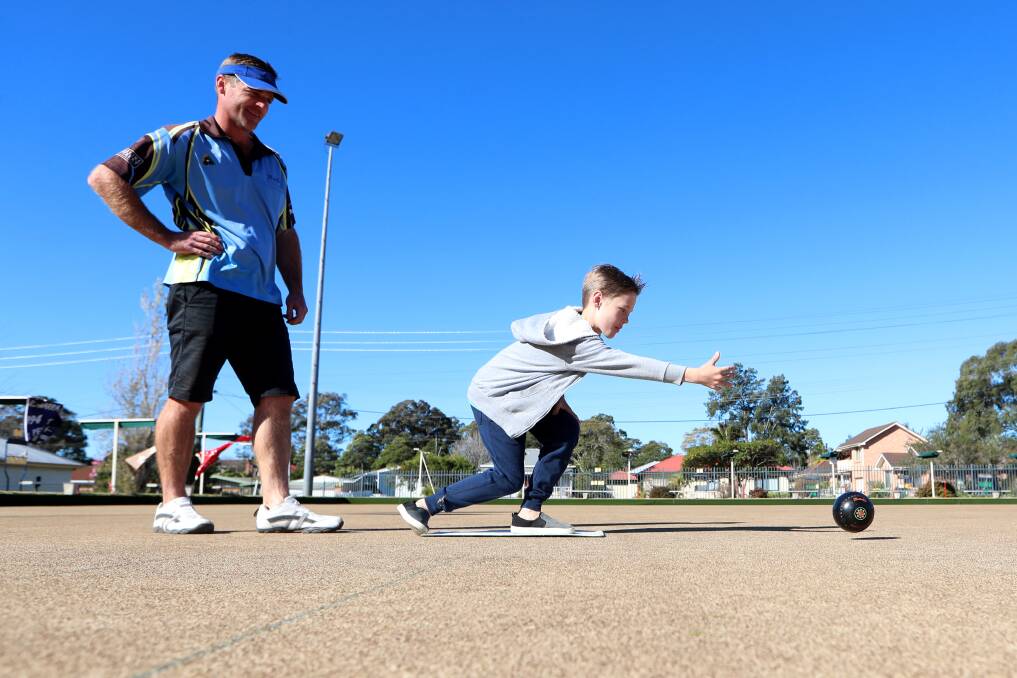 Brad Whitford watches on as his son, 10-year-old Blake, sends one down the green during the Dapto Bowling Club's final days this week. Picture: Sylvia Liber