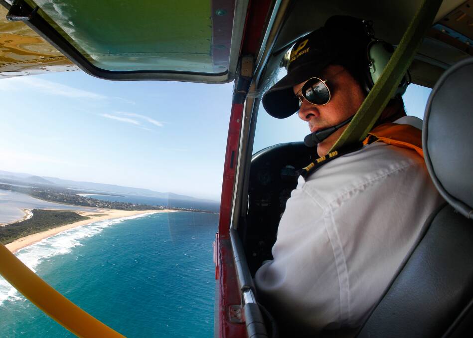 EYES IN THE SKY: Bendigo Bank Aerial Patrol pilot Adam Brady looks over Illawarra beaches during a recent flyover. Picture: Sylvia Liber 