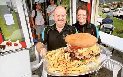 Rapt: East Corrimal fish and chip shop owners Tony and Melissa Neale with their enormous $36 burger.