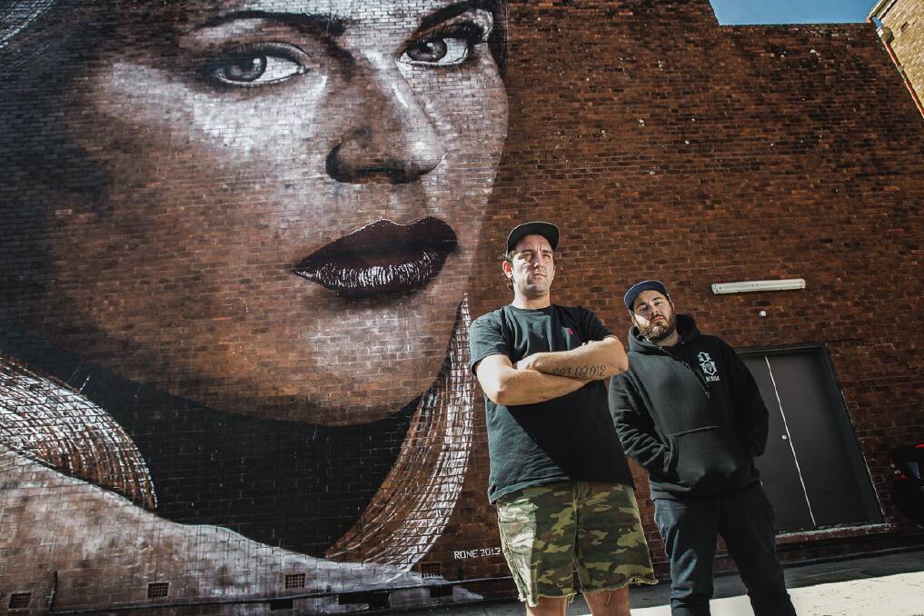 Wonderwalls Wollongong festival founder Simon Grant, right, and artist Mitch Guerin in front of a mural created by Melbourne artist Rone at last year's event. Picture: CHRISTOPHER CHAN