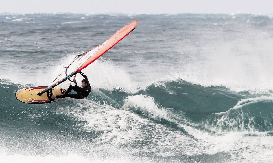 A windsurfer gathers speed at Cowrie Island, Shellharbour, during yesterday’s wild weather. Picture: DAVE TEASE