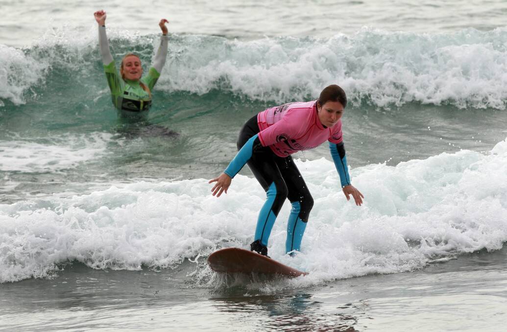 Surfing instructor Stephanie Power watches while student Rebecca Markey catches a wave. The sport acts as a great workout and stress valve.