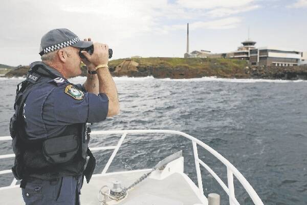 Snr Const Garry Webster, of Port Kembla Water Police, searches for the missing fisherman off the breakwater at Port Kembla. Picture: GREG TOTMAN