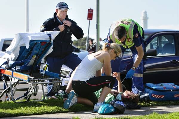 A cyclist with a puncture wound to the chest is treated by paramedics after being knocked from his bike. Picture: KEN ROBERTSON