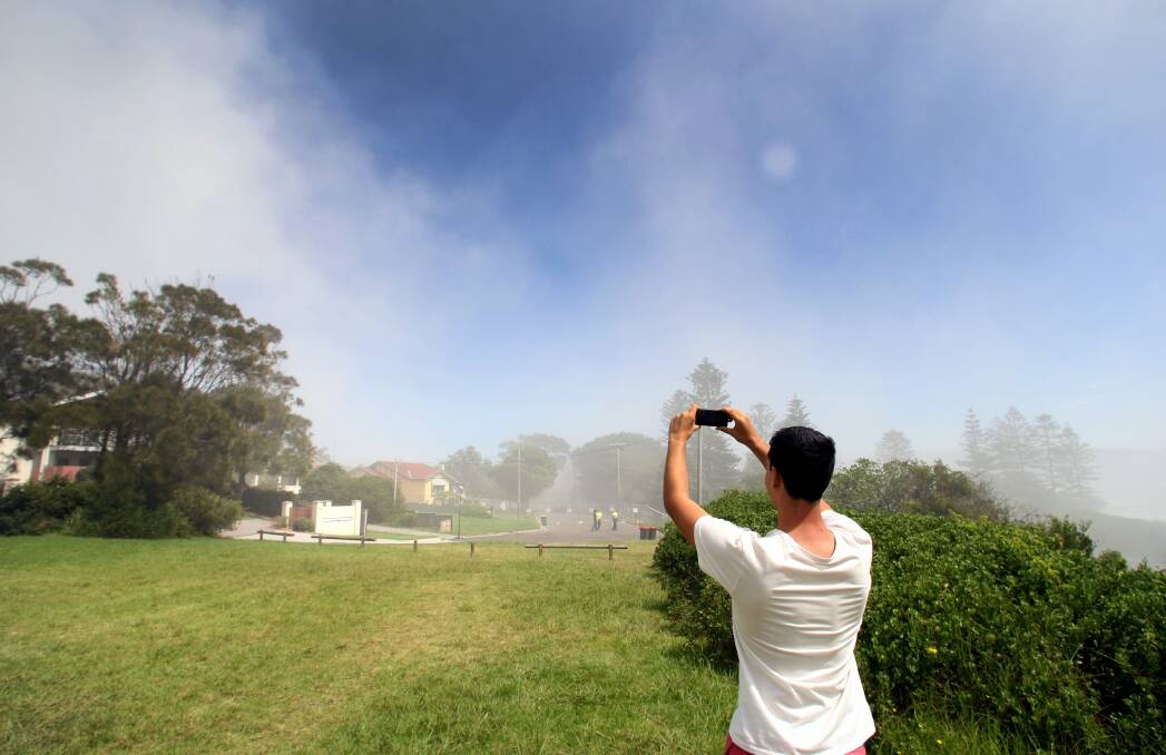 An onlooker captures the aftermath of the stack's demolition last week. Port Kembla Copper says it could take three months before rubble is completely removed. Picture: ORLANDO CHIODO