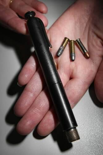 A police officer holds a .22 calibre pen gun and three live rounds. Picture: KEN ROBERTSON