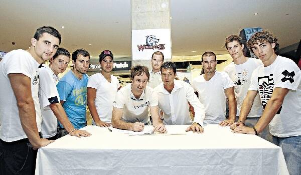 A host of Wolves players stand behind new coach Trevor Morgan (centre) and player Brody Paine as they sign contracts in Wollongong. Picture: SYLVIA LIBER