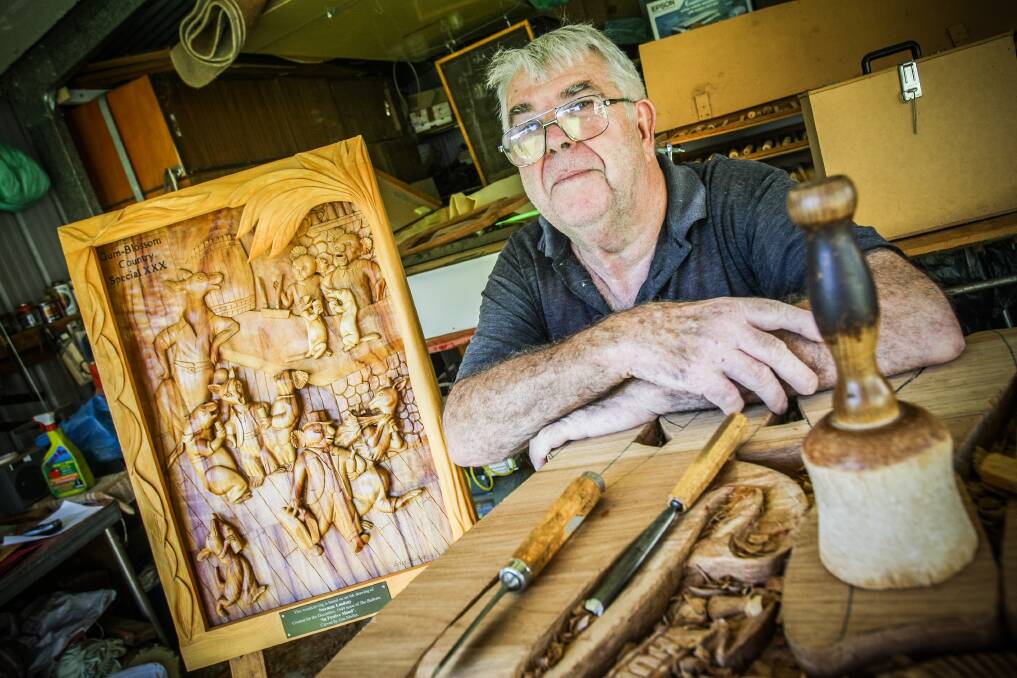 Oak Flats woodcarver Enn Muller with one of his magnificent works, a carving of Norman Lindsay’s painting In Festive Mood. Picture: DYLAN ROBINSON