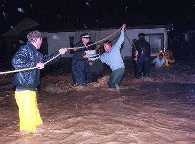 Police and workers help a family to safety from a flooding house in Figtree in 1998.