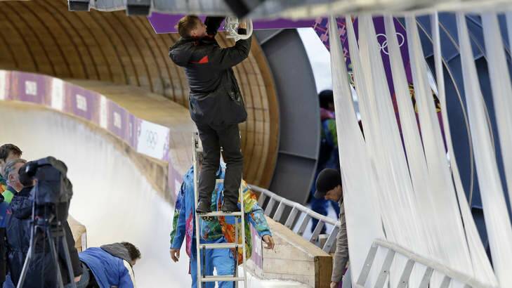 Sudden impact ... A track worker repairs some lights that were damaged after a worker was hit by a forerunner bobsleigh. Photo: AP Photo