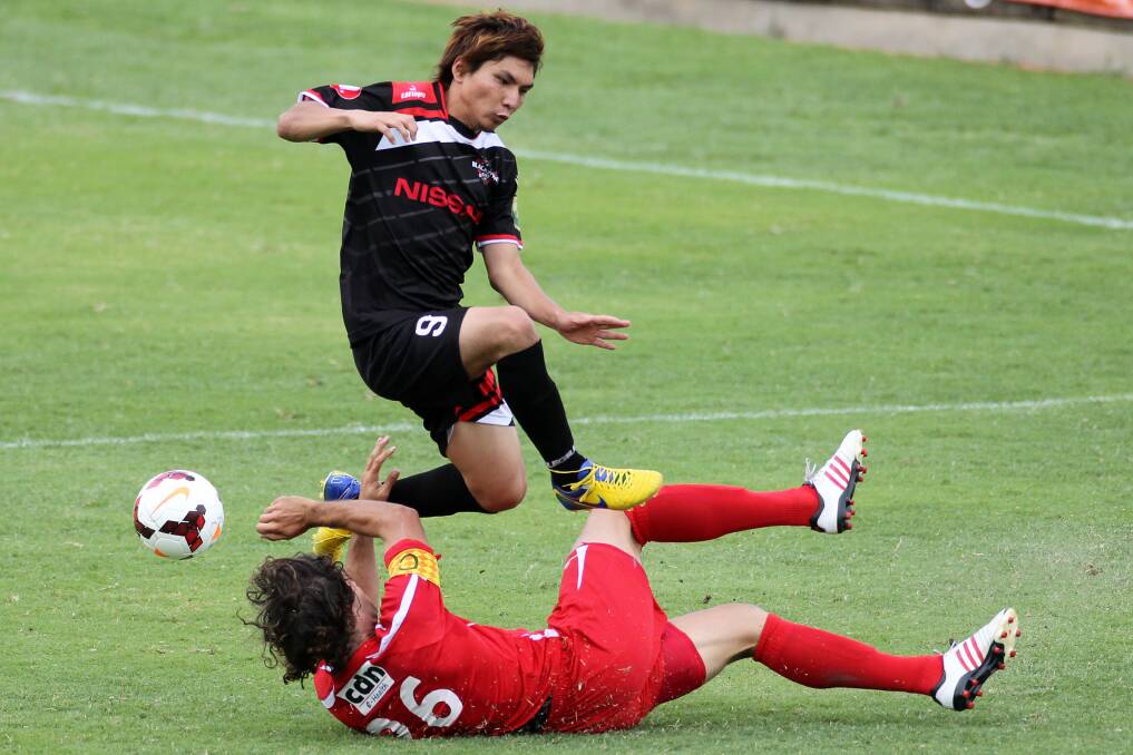 Close call: Blacktown City’s Ryuji Miyazawa leaps to avoid a nasty collision with South Coast Wolves’ Jacob Timpano at WIN Stadium on Sunday. Blacktown totally dominated the match to win 5-0. Picture: GREG TOTMAN