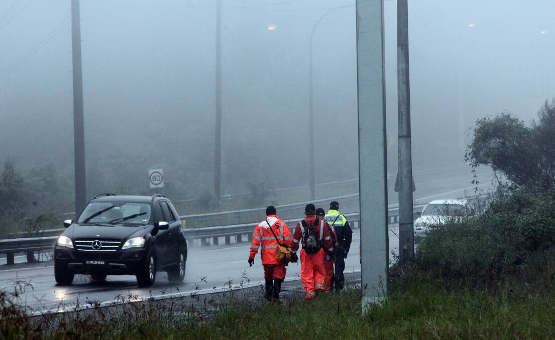 Police and SES personnel walk along the Princes M1 Motorway at Bulli Tops. Picture: KIRK GILMOUR
