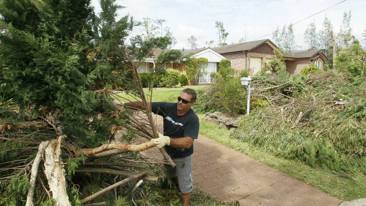 Jamberoo's Andrew Smith cleans up the remains of trees on his property felled during the storm