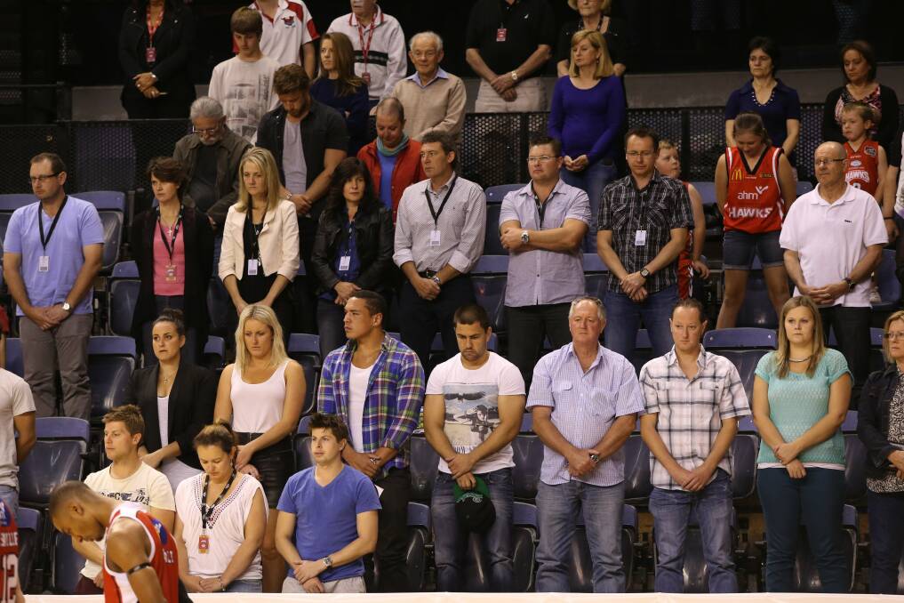 Hawks' fans, including Dragons player Jamie Soward (front row middle) bow their heads for a minute's silence.