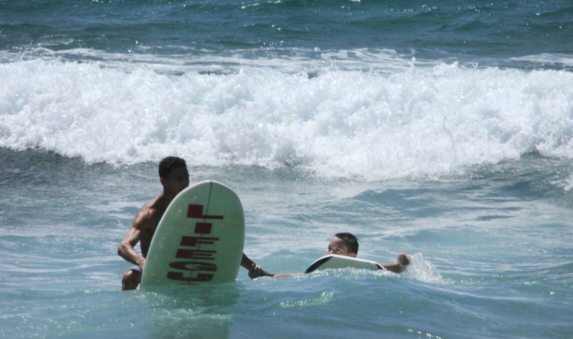 Lifeguard Dillon Ruiz rescues a boy from the surf at Austinmer. Picture: KIRK GILMOUR