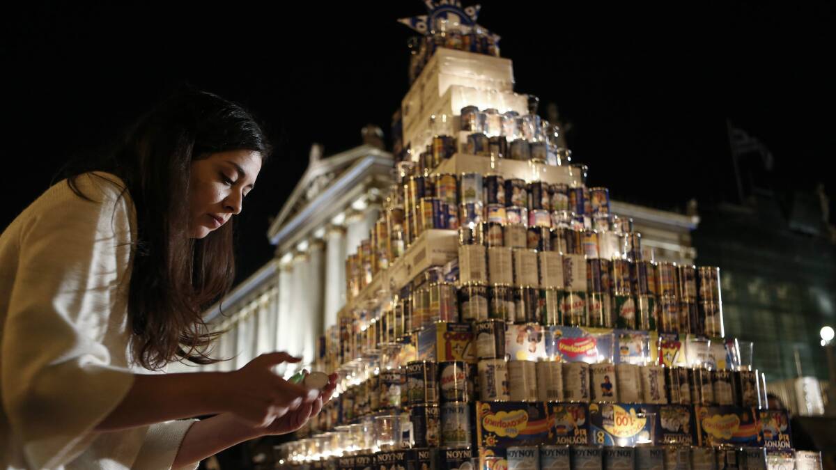 A woman lights a candle in Athens, Greece.  Picture: REUTERS