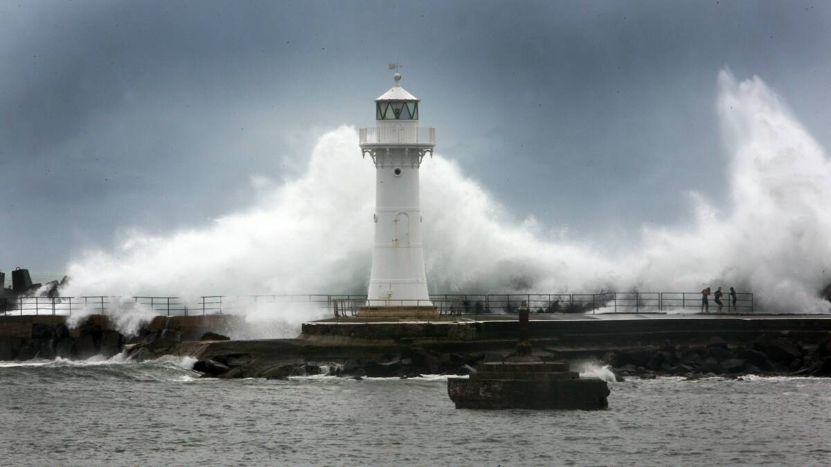 The Wollongong Breakwater Lighthouse stands in the path of a huge wave at Wollongong Harbour. Pictures: ROBERT PEET, ANDY ZAKELI and DYLAN ROBINSON