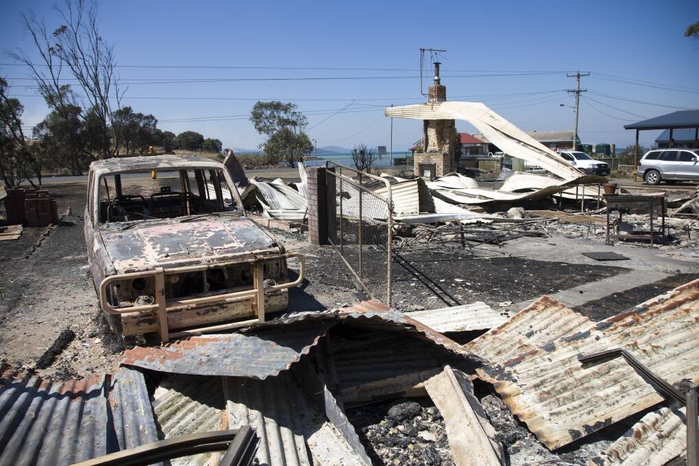 Charred remains of a car and houses at Dunalley. Photo: Peter Mathew