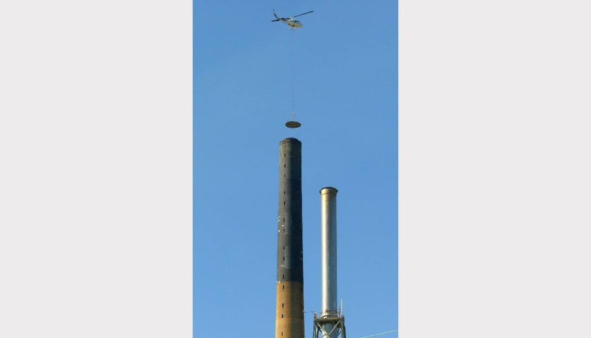 A helicopter lowers the one-tonne steel disc to the top of Port Kembla Copper's main stack.