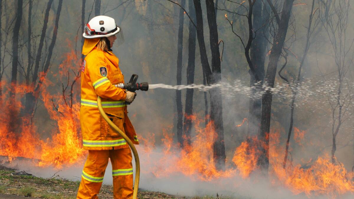 An RFS member putting out a spot fire on the side of Picton Road. Picture: ADAM McLEAN
