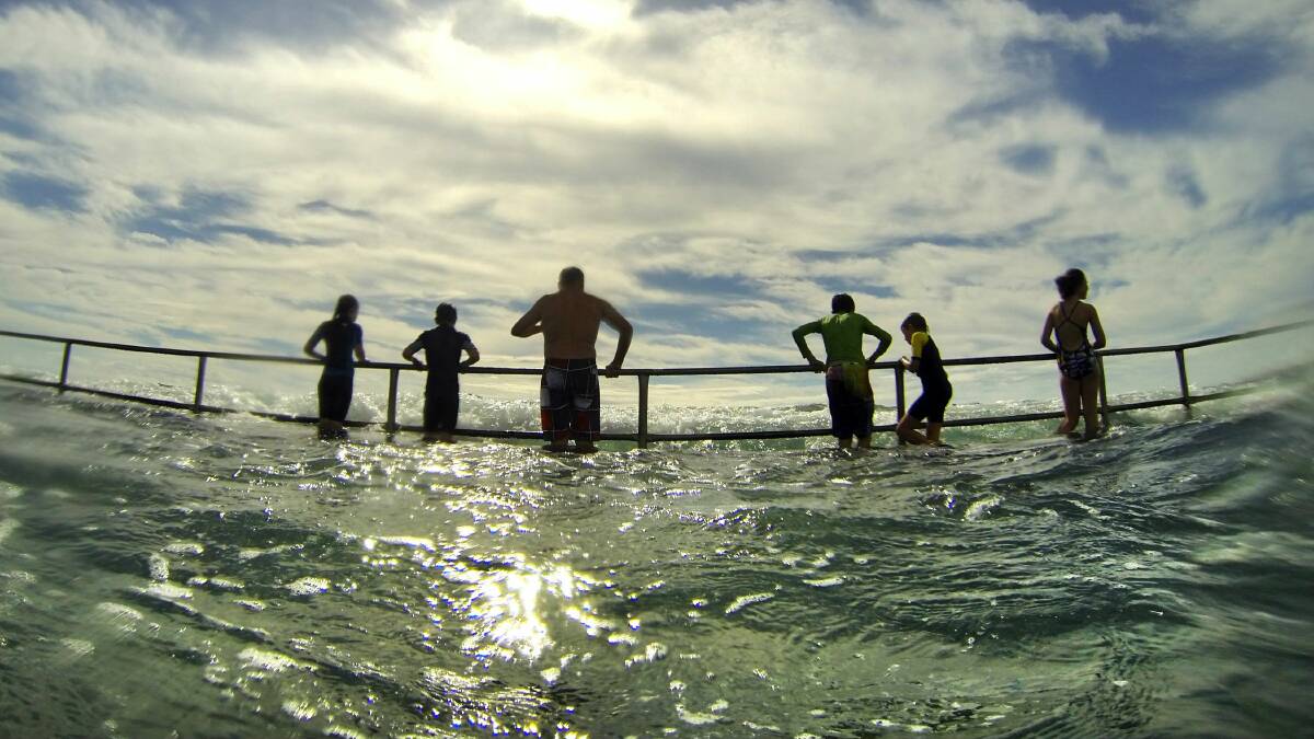 The king tide of two metres at 9.30am entertains swimmers at the pool at Austinmer Beach. Picture: KIRK GILMOUR