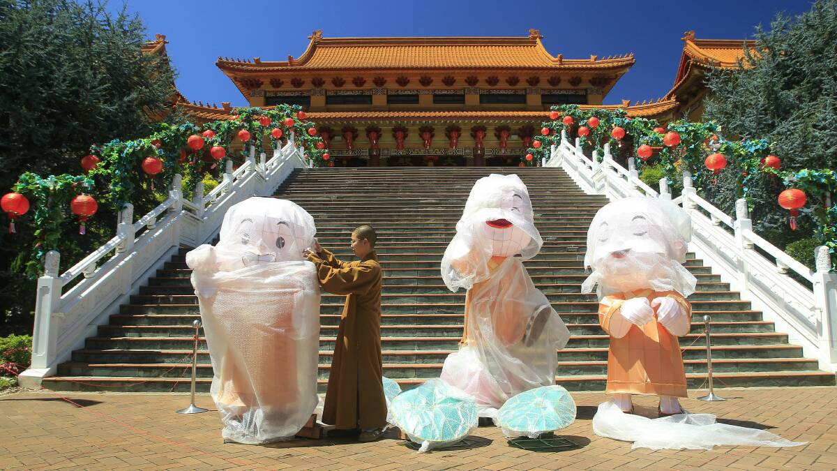 The Venerable Zhi Shan at the Nan Tien Temple unwraps the three monks statues for the New Year celebrations. Picture: ANDY ZAKELI
