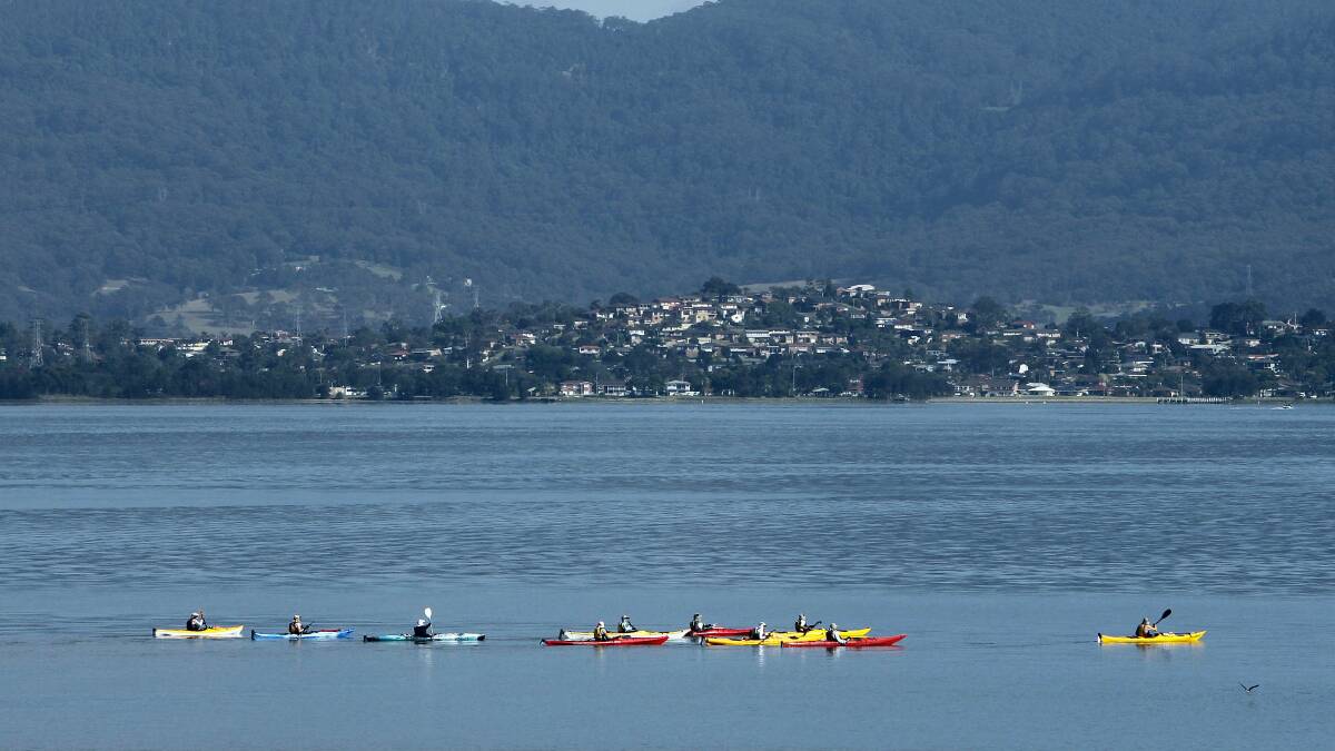Kayakers paddle past Boonerah Point on Lake Illawarra on a clear summer’s day yesterday. Picture: ANDY ZAKELI